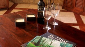 Ein Holztisch mit einer Weinflasche, zwei Gläsern und einem Buch mit dem Titel 'El Parque de la Canaria'.