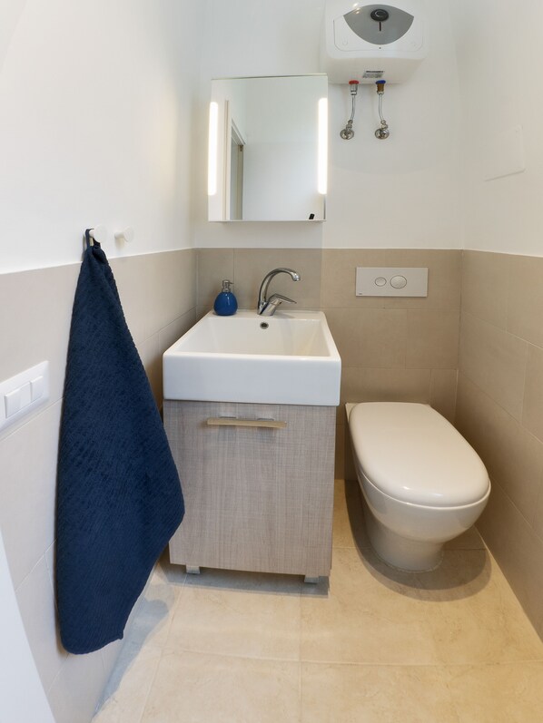 A bathroom with a white sink, a mirror, a toilet, and a towel rack.