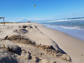 A beach with sand, waves, and a clear sky.