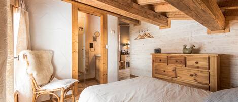 A bedroom with a wooden ceiling, a bed, a dresser, and a chair.