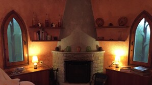 A cozy room with a stone fireplace, two windows with frosted glass, and shelves with decorative items. - Secluded house with pool, barbecue and garden 10min. of the beach. Ideal families (Calonge)