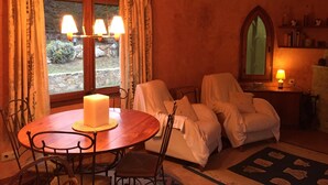 A cozy room with a round wooden table, two chairs, a large candle, and a window with curtains. - Secluded house with pool, barbecue and garden 10min. of the beach. Ideal families (Calonge)