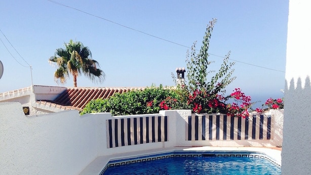 A swimming pool with a clear blue water, surrounded by white walls and a red-tiled floor. - Casa with Private Pool, Sea Views, Mountain views and Peaceful Location (Nerja)