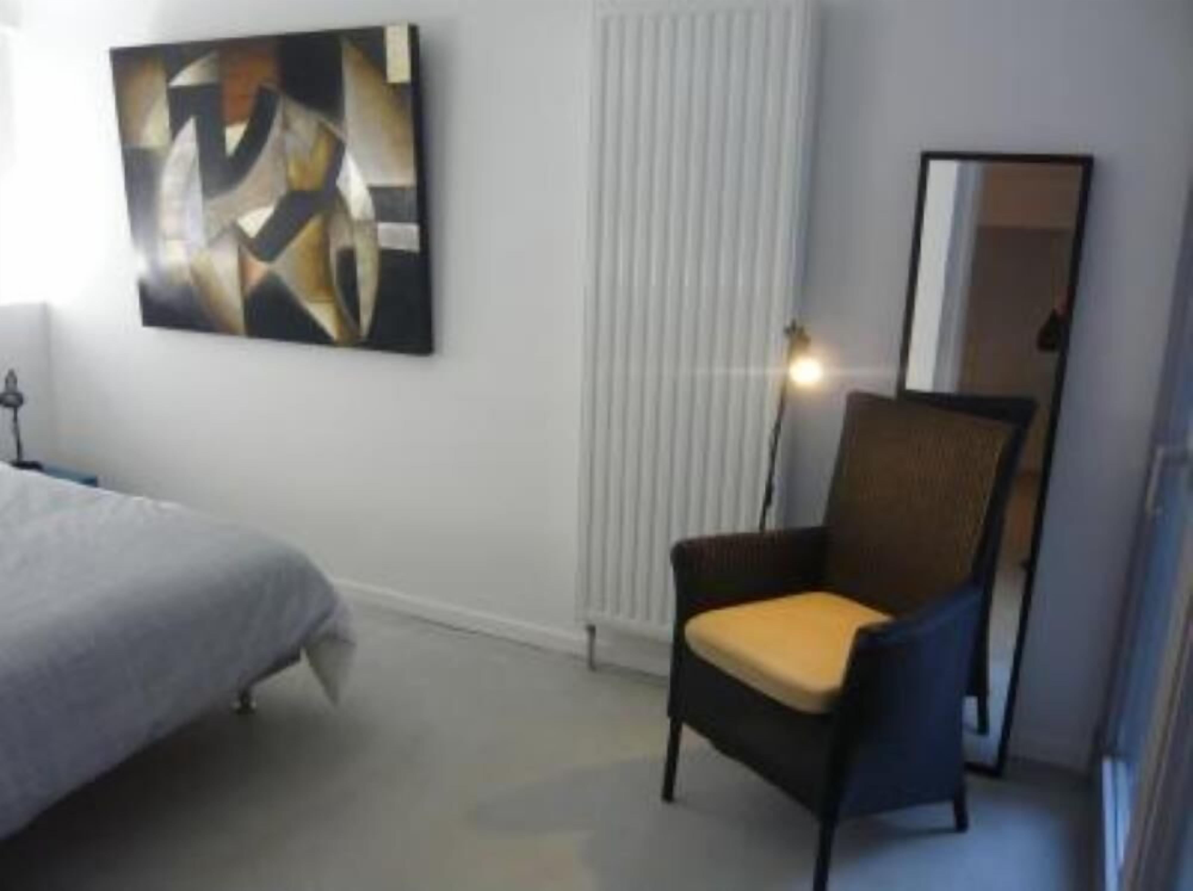 Habitación de hotel con cama, una silla, un cuadro en la pared y ventana con persianas.
