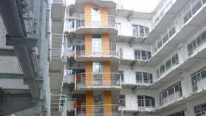 Un edificio de varios pisos con un atrio central, balcones y un estacionamiento.