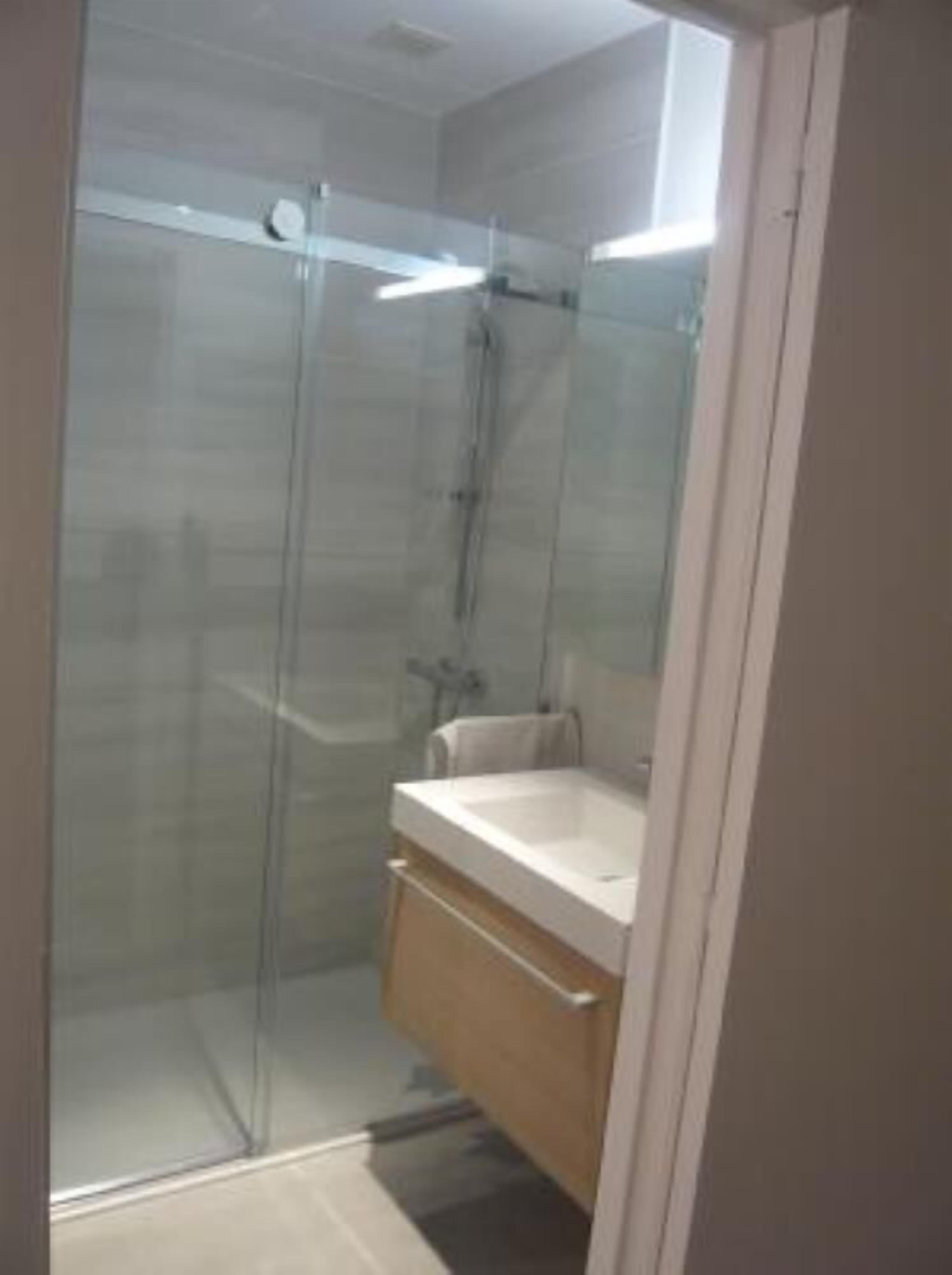 A modern bathroom with a glass shower enclosure, a sink, and a wooden vanity.