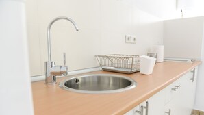 Una cocina moderna con un lavamanos de acero inoxidable, encimera de madera y armarios blancos.