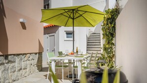A patio with a table and chairs, a yellow umbrella, and a potted plant.
