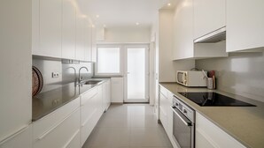 A modern kitchen with white cabinets, a stainless steel sink, a microwave, and a built-in oven.