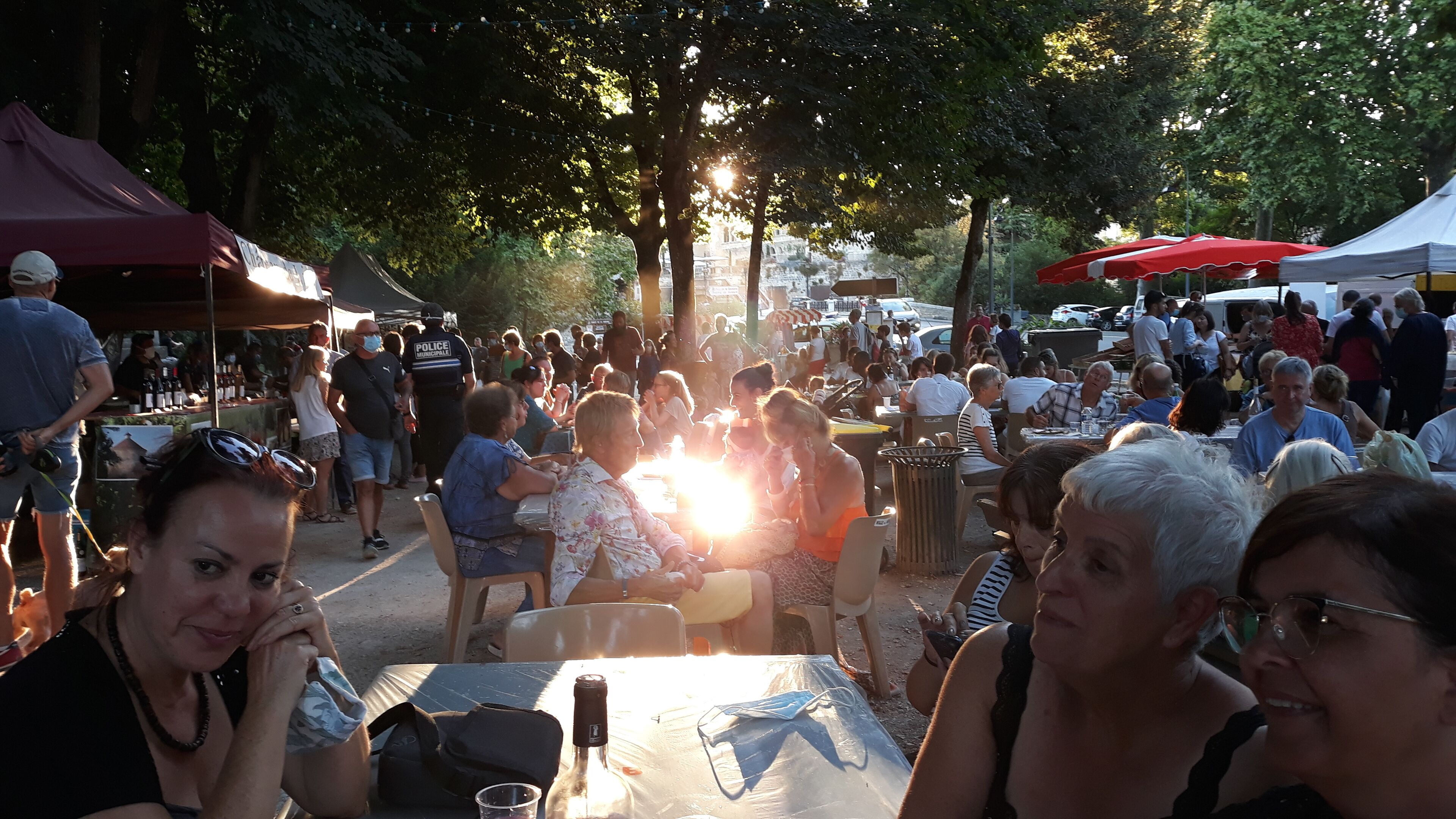 A crowded outdoor market with people sitting at tables under tents.