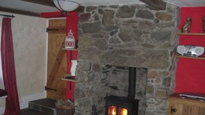 Een stenen openhaard met vuur, houten planken en een rode wand.