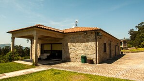 Un edificio de piedra con techo de tejas, un patio cubierto y vistas del paisaje circundante.