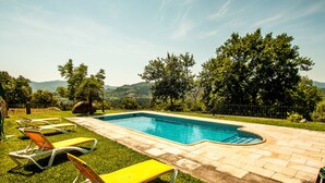 Una piscina con un borde de baldosas y sillas de descanso.