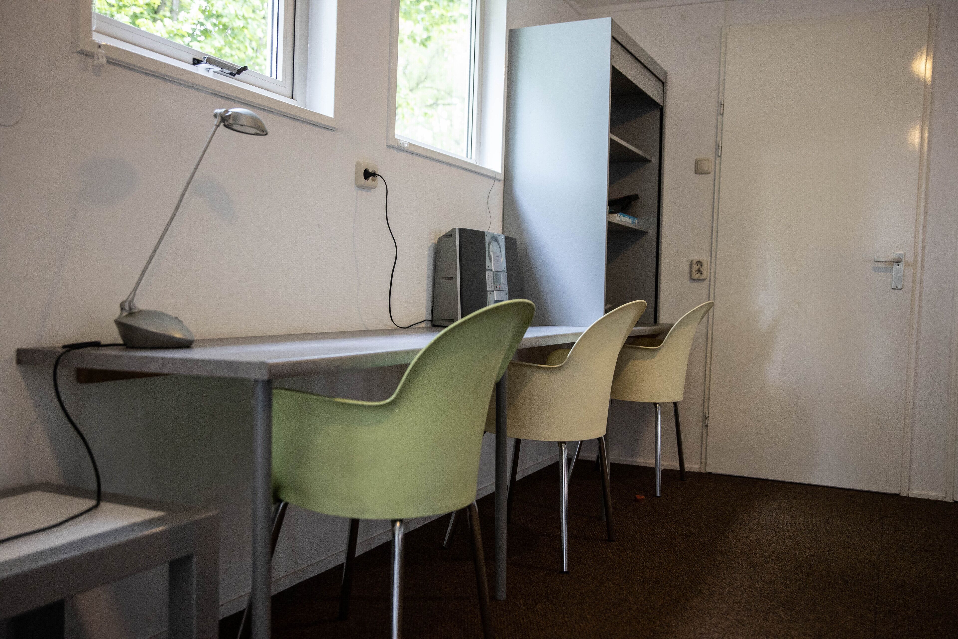 Een kamer met een bureau, twee stoelen, een lamp en een computer.
