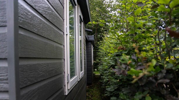 A house with a dark siding exterior and a window. - Spacious & cozy holiday bungalow "Frank" in wooded area (12 people) (Den Ham)
