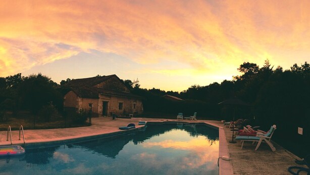 Una piscina con sillas de descanso y una casa al fondo.