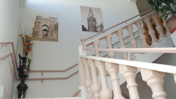 A staircase with a white balustrade, a black vase with flowers, and two black-and-white photographs on the wall. - Rural House Jardin del Arroyo. (El Viso de San Juan)