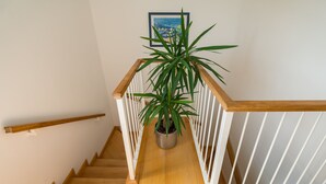 Una escalera de madera con barandas blancas y una planta en maceta en la parte superior.