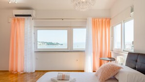 Una habitación de hotel con una cama grande, vista al mar y una ventana con cortinas.