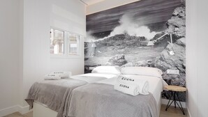 Un dormitorio con dos camas, un mural grande en la pared y un taburete de madera.