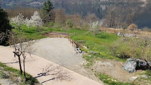 A scenic view of a lake with a wooden bridge, surrounded by green fields and trees. - LAKE ORTA - LAKE VIEW APARTMENT, PRIVATE BEACH AND BALCONIES (FIRST FLOOR) (Pettinasco)