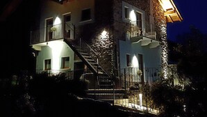A multi-story building with a stone facade, a balcony on the upper floor, and a staircase leading to the entrance. - LAKE ORTA - LAKE VIEW APARTMENT, PRIVATE BEACH AND BALCONIES (FIRST FLOOR) (Pettinasco)