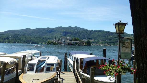 A dock with boats, a wooden pier, and a mountain backdrop. - LAKE ORTA - LAKE VIEW APARTMENT, PRIVATE BEACH AND BALCONIES (FIRST FLOOR) (Pettinasco)