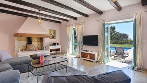 Uma sala de estar ampla com lareira, televisão e vista para uma piscina.