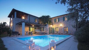 Uma casa de pedra com piscina, área de estar externa e lanternas.