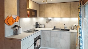 Una cocina moderna con horno empotrado, cafetera y hervidor.