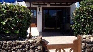 Un bâtiment avec un mur en pierre, une table en bois et un parasol bleu.