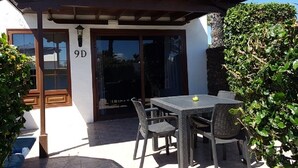 Une terrasse avec une table et des chaises, un espace abrité et une porte portant le numéro 9D.