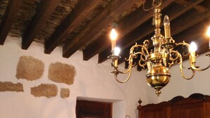 Une pièce avec une porte en bois, un lustre, une table avec une lampe et un tapis à rayures.