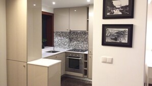 A compact kitchen with a tiled backsplash, stainless steel appliances, and a small oven. - I Love Alegria - cosy Studio (Porto)