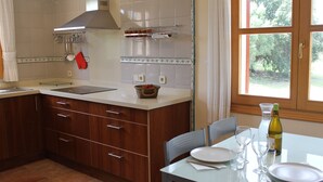 A kitchen with wooden cabinets, a white countertop, and a dining table set for two with wine glasses and a bottle. - Cozy, quiet house with Pool, Wifi and sea view (Son Servera)