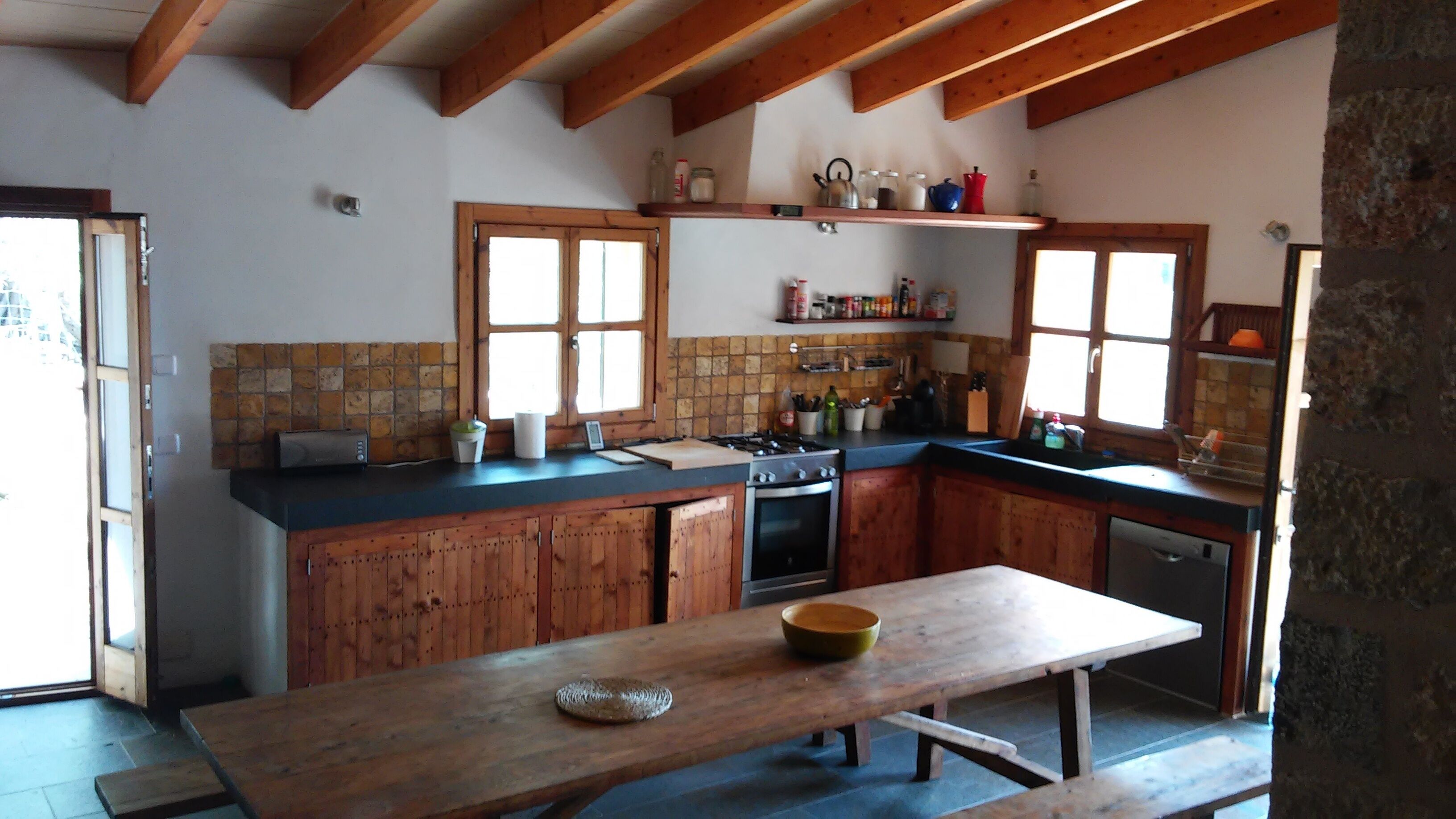 A rustic kitchen with wooden cabinets, a central island, and a built-in oven.