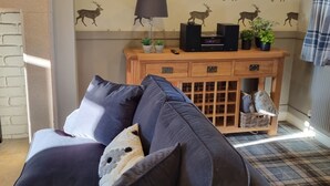A living room with a sofa, a fireplace, a wall with deer decals, a console table with a lamp, and a patterned rug. - 2 Bedroom Luxury Cottage close to Bakewell, in the stunning Peak District (Over Haddon)