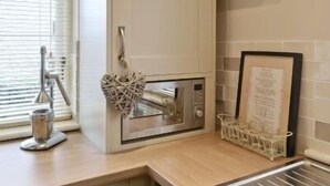 A kitchen with a built-in oven, a sink, and a window with blinds. - 2 Bedroom Luxury Cottage close to Bakewell, in the stunning Peak District (Over Haddon)