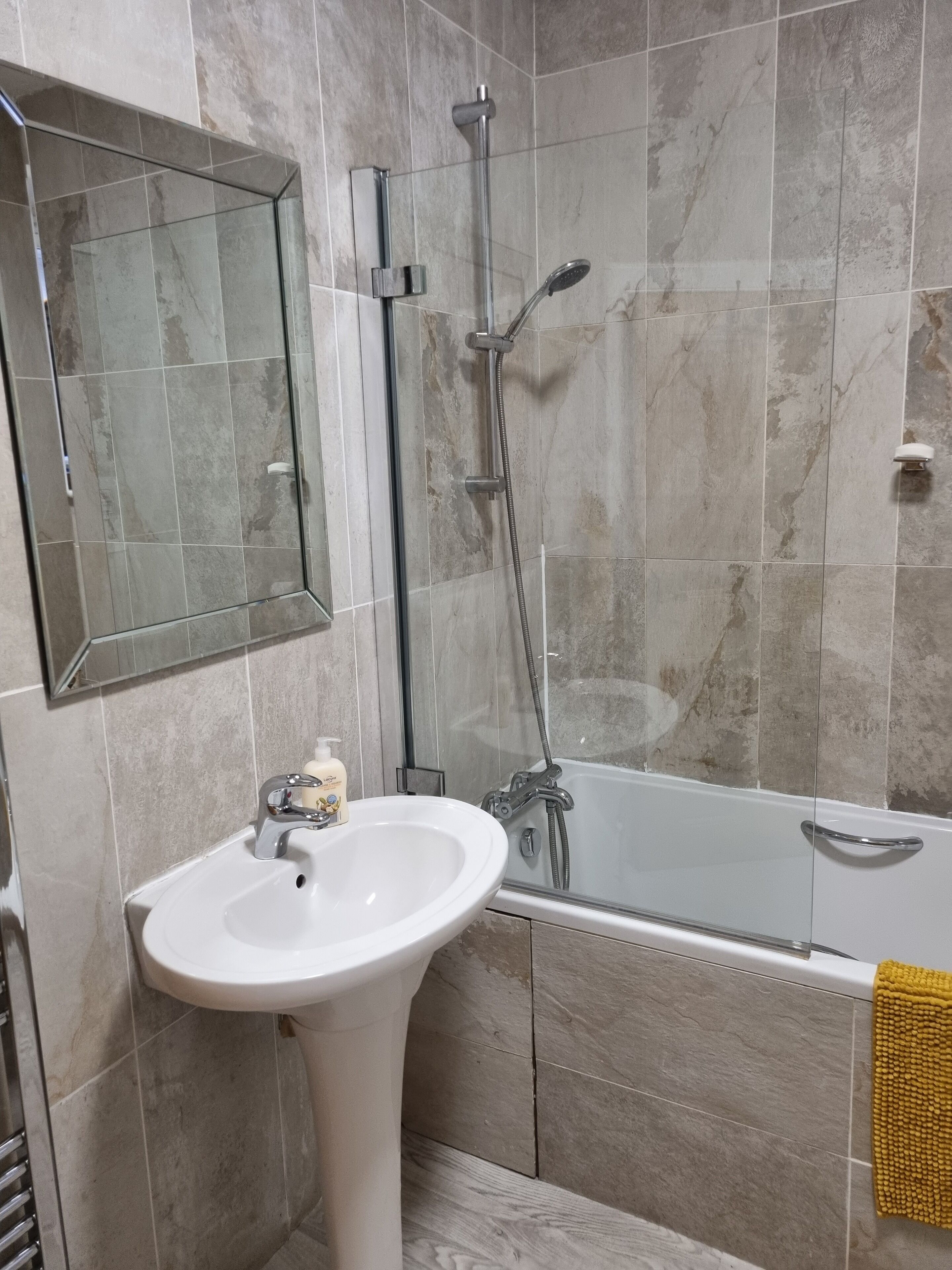 A bathroom with a white sink, a glass shower enclosure, and a bathtub.