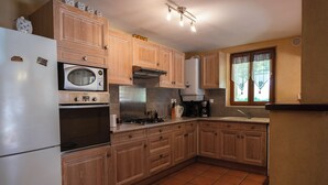 A kitchen with wooden cabinets, a refrigerator, an oven, a microwave, and a stove. - Character house in the heart of the Luberon Park (Gargas)