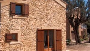 A stone building with wooden shutters, a door, and a window. - Character house in the heart of the Luberon Park (Gargas)