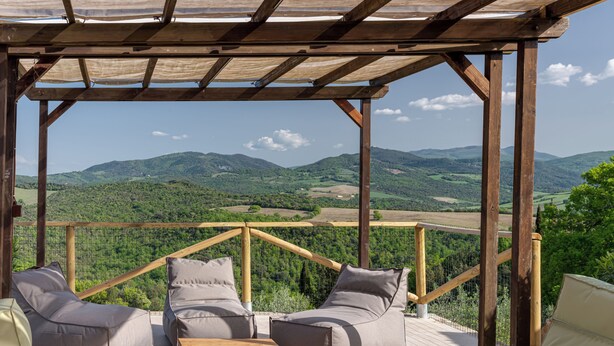 A wooden deck with outdoor seating and a view of green hills. - Country House & Spa - Inside Nature with panoramic views, Art Surrounded (Volterra)