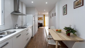 A modern kitchen with white cabinets, stainless steel appliances, and a wooden dining table with chairs.