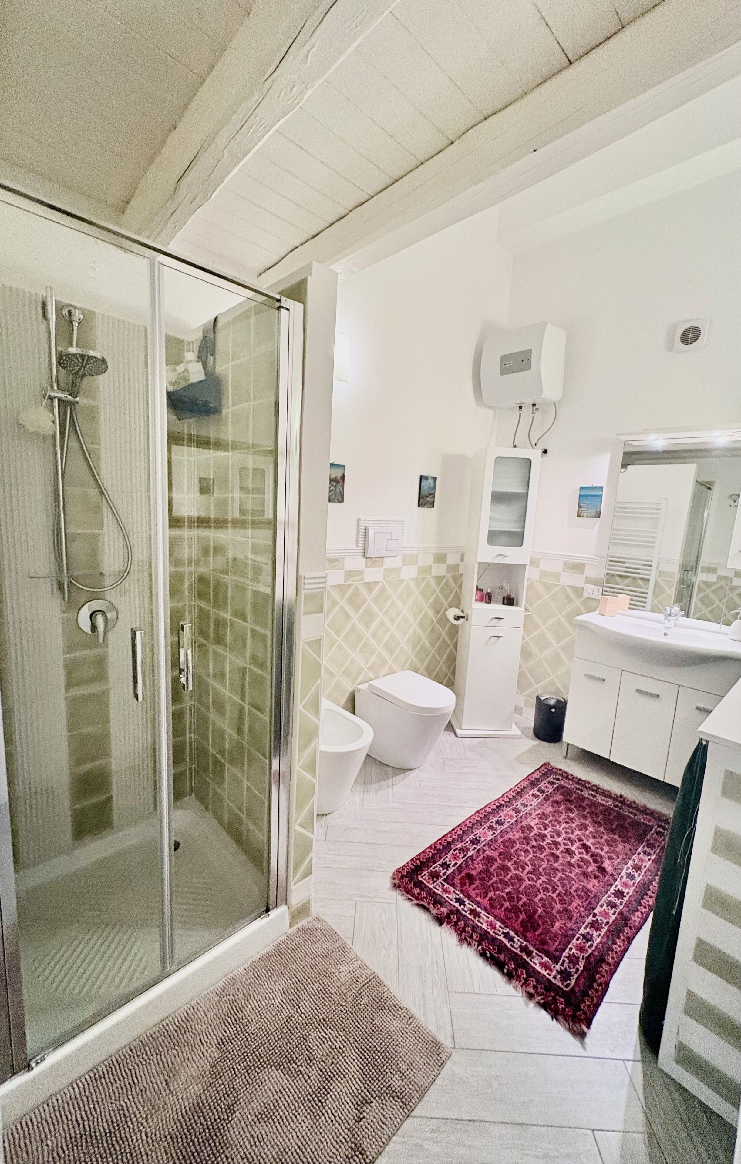 A bathroom with a glass shower enclosure, a toilet, a sink, and a mirror.