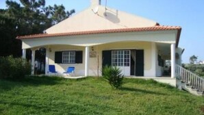 Una casa de un piso con techo de tejas, un porche cubierto y un pequeño jardín.