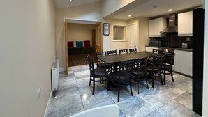 A dining area with a large table and chairs, a kitchen with modern appliances, and a skylight above the table. - The Townlets Townhouse - 5BR - sleeps 13 (Belfast)
