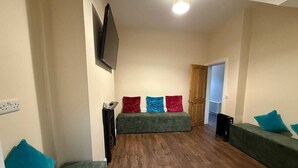 A room with a green sofa set, a flat-screen TV mounted on the wall, and a wooden floor. - The Townlets Townhouse - 5BR - sleeps 13 (Belfast)