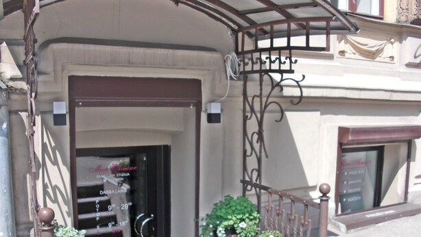 A building entrance with a staircase leading to the door, a wrought iron railing, and flower boxes with various plants. - SUNNY LOUNGE GRAND APARTMENT (Riga)