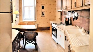 A compact kitchen with a dining table, chairs, a stove, and a sink. - SUNNY LOUNGE GRAND APARTMENT (Riga)