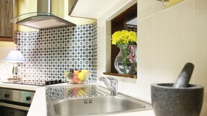 A kitchen with a stainless steel sink, a stone mortar, and a bowl of fruit. - Perfect! for doing Galway City - sleeps 2+, walk everywhere... (Devon Place The Crescent Galway City)